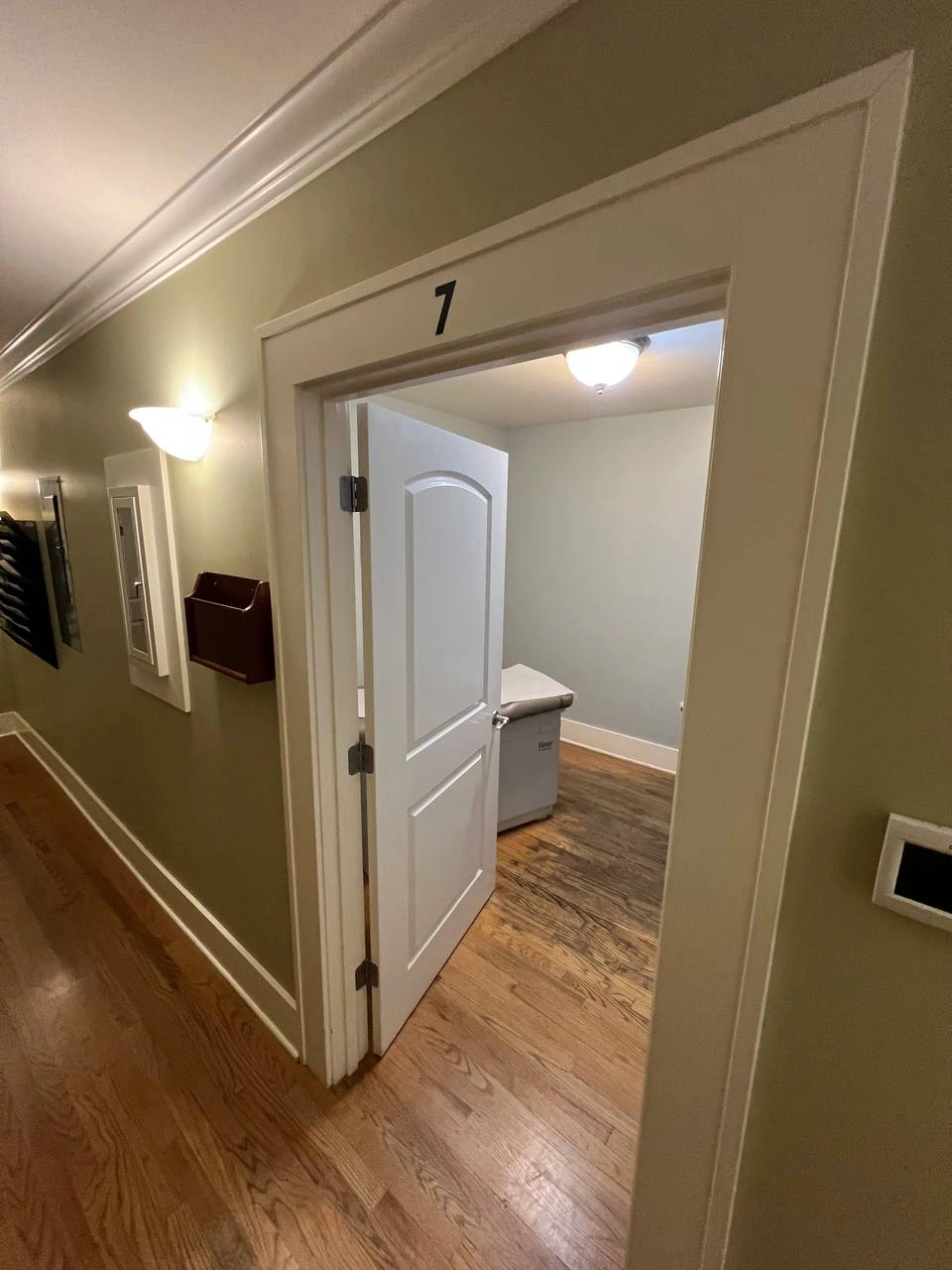 Open doorway to medical room seven showing aged wood flooring before professional renovation.
