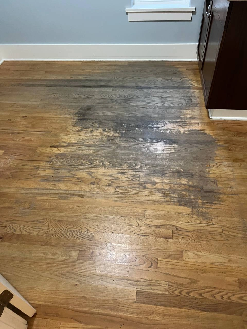 Close-up of stained and darkened hardwood flooring planks before any sanding or replacement work is performed.