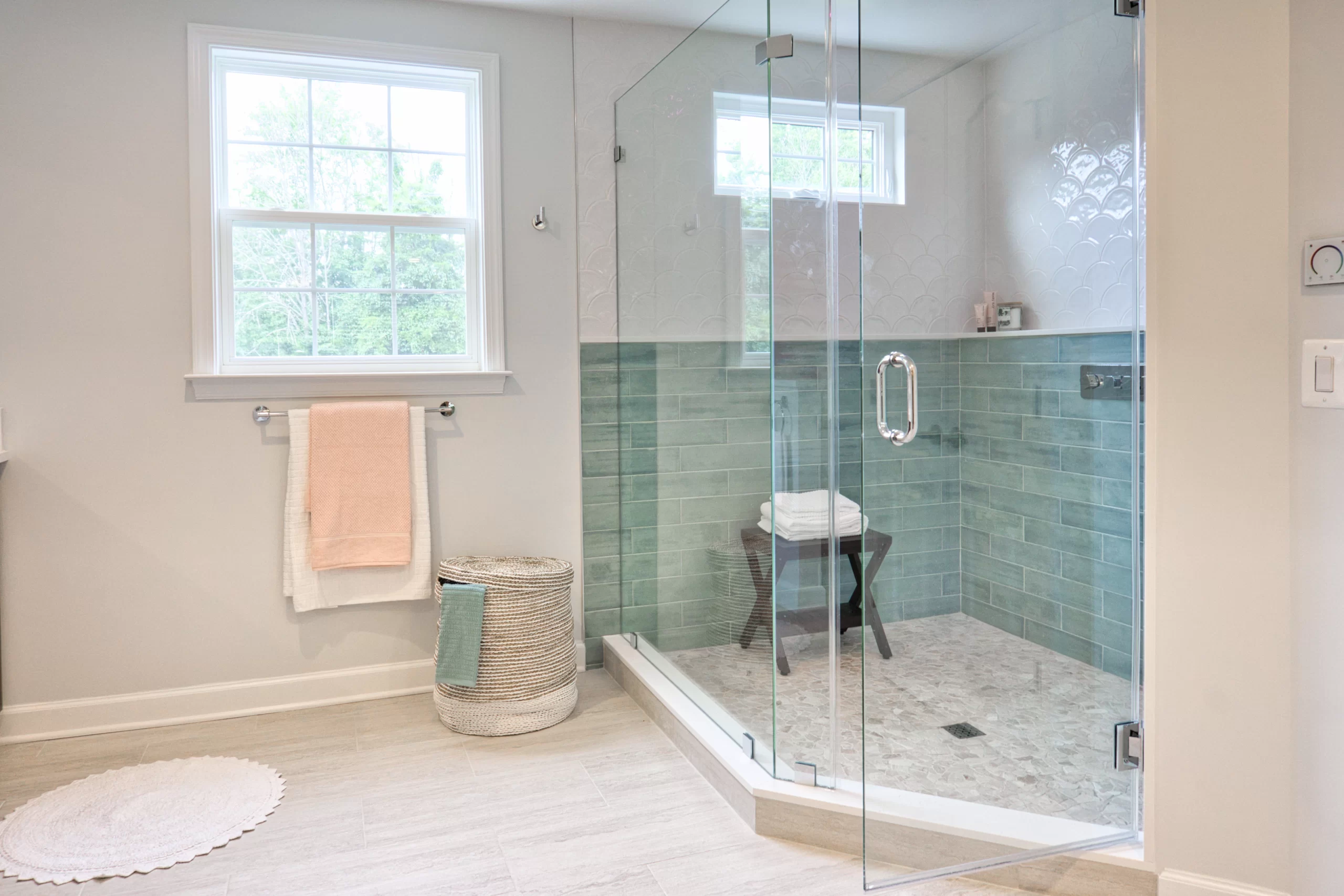 Large frameless Shower Glass Doors open to a walk-in shower with teal subway tiles and a window.
