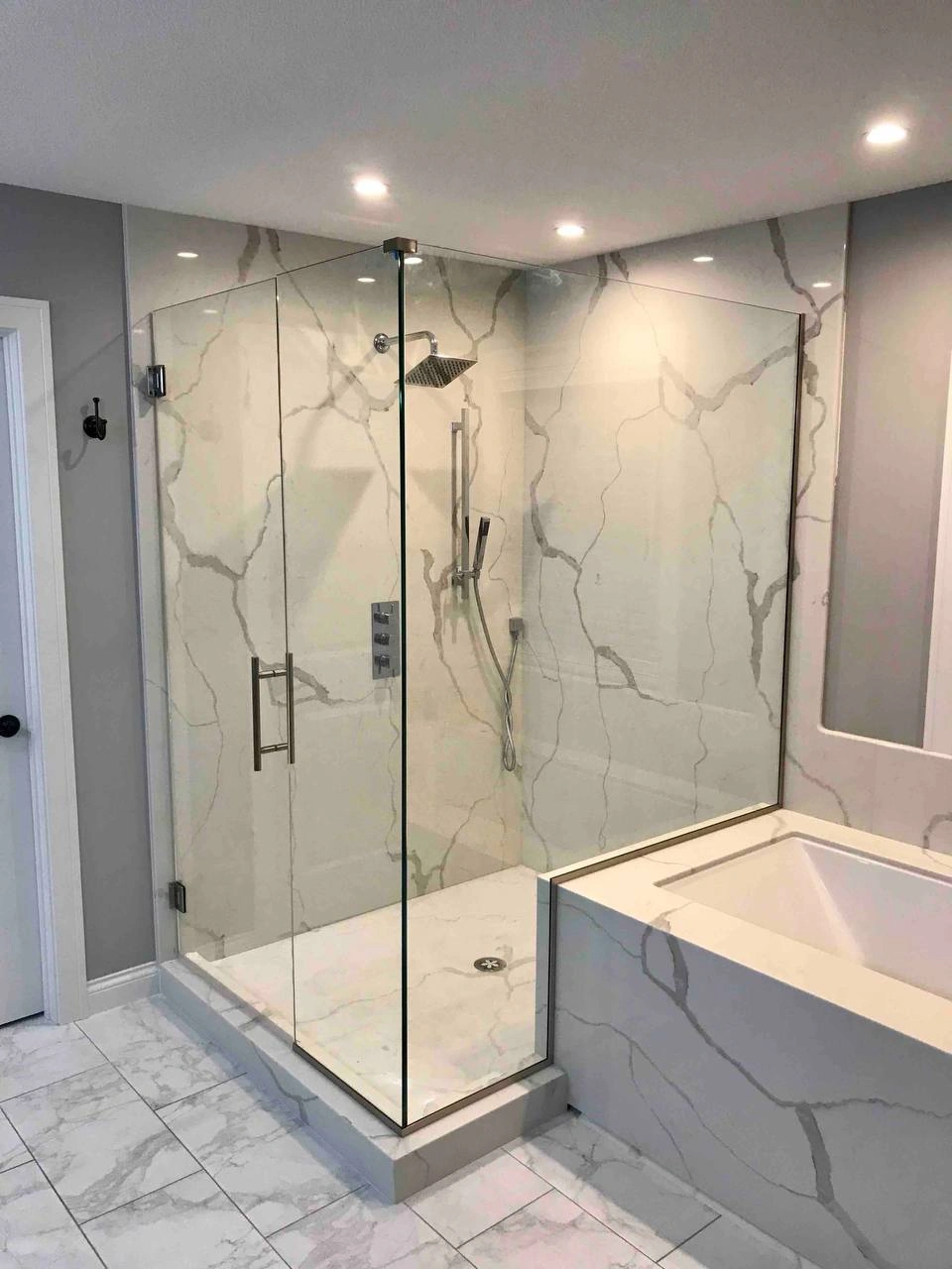 Luxurious walk-in shower featuring frameless Shower Glass Doors and elegant marble-patterned wall tiles.