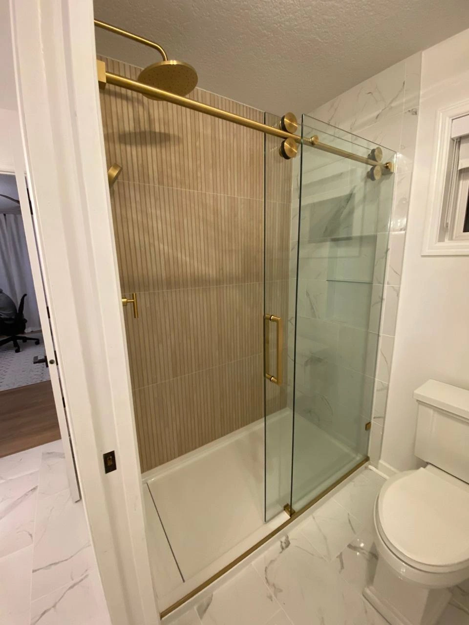 Frameless sliding Shower Glass Doors featuring elegant gold rollers and a matching towel bar handle.