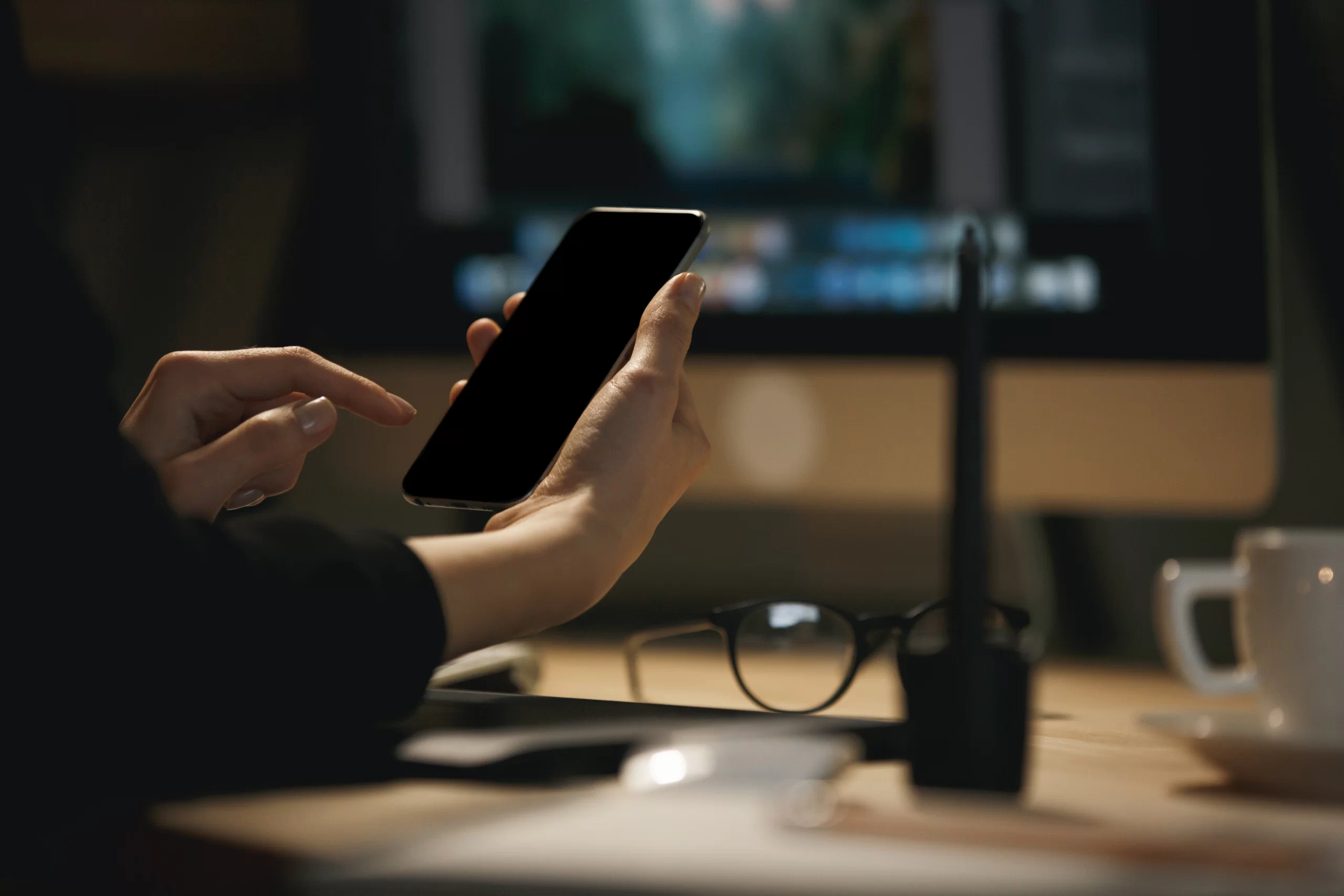 Hands holding a smartphone at a desk while researching home renovation financing options online.